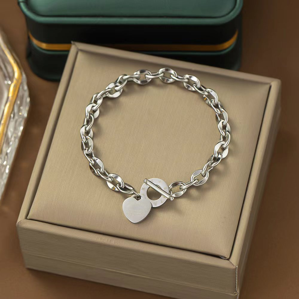 Brazalete Plateado de Cadena con un Dije de Corazón y un Cierre de Barra en T